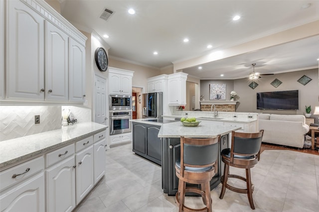 kitchen with visible vents, open floor plan, a peninsula, stainless steel appliances, and crown molding