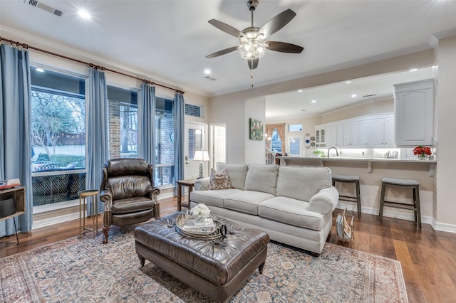 living area with ornamental molding, visible vents, plenty of natural light, and wood finished floors