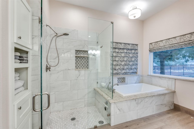 full bathroom featuring a garden tub, a shower stall, and wood finished floors