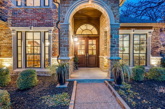 entrance to property featuring stone siding and brick siding