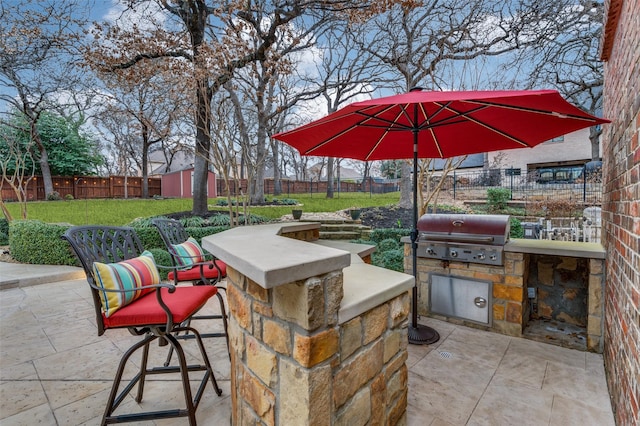 view of patio featuring exterior kitchen, a fenced backyard, and area for grilling