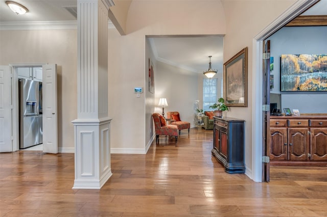 interior space featuring ornate columns, baseboards, crown molding, and wood finished floors