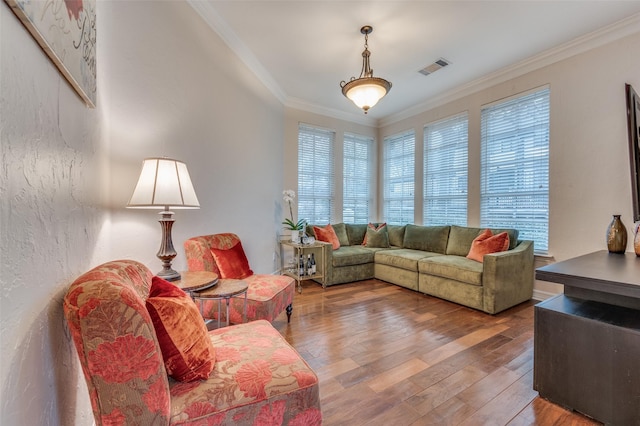 living room featuring a textured wall, visible vents, crown molding, and wood finished floors