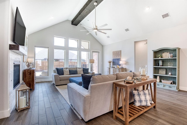 living room featuring a glass covered fireplace, a healthy amount of sunlight, visible vents, and wood finished floors