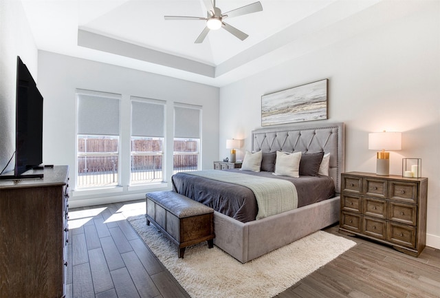 bedroom featuring a tray ceiling, ceiling fan, and wood finished floors