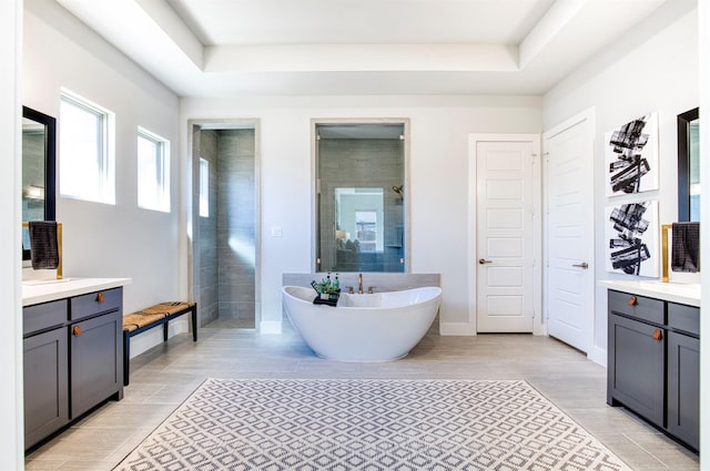 full bathroom with a soaking tub, a shower stall, a tray ceiling, and vanity