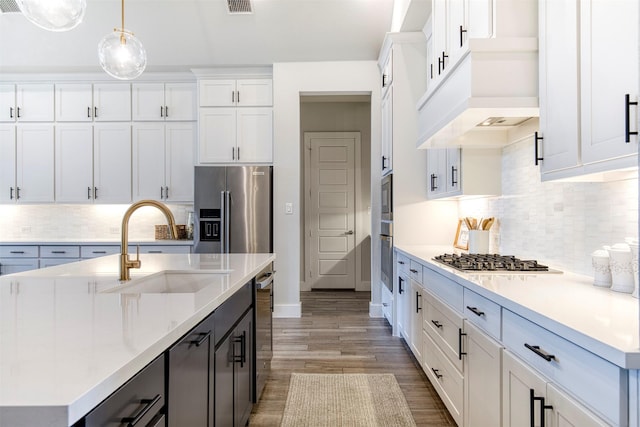 kitchen with light countertops, appliances with stainless steel finishes, custom exhaust hood, and a sink