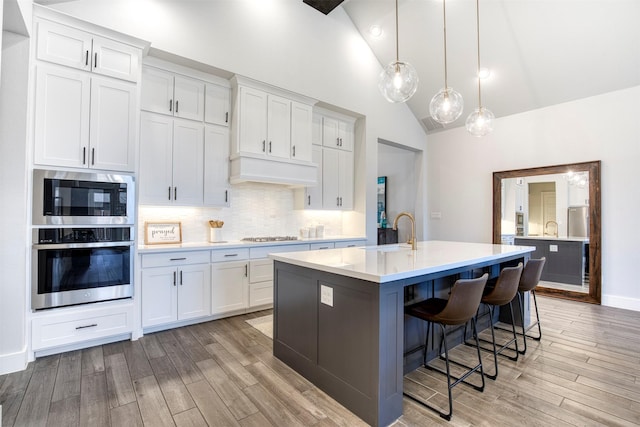 kitchen with stainless steel appliances, light countertops, light wood-style flooring, a sink, and premium range hood