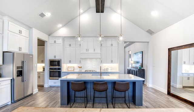 kitchen with stainless steel appliances, light countertops, visible vents, white cabinets, and a kitchen breakfast bar