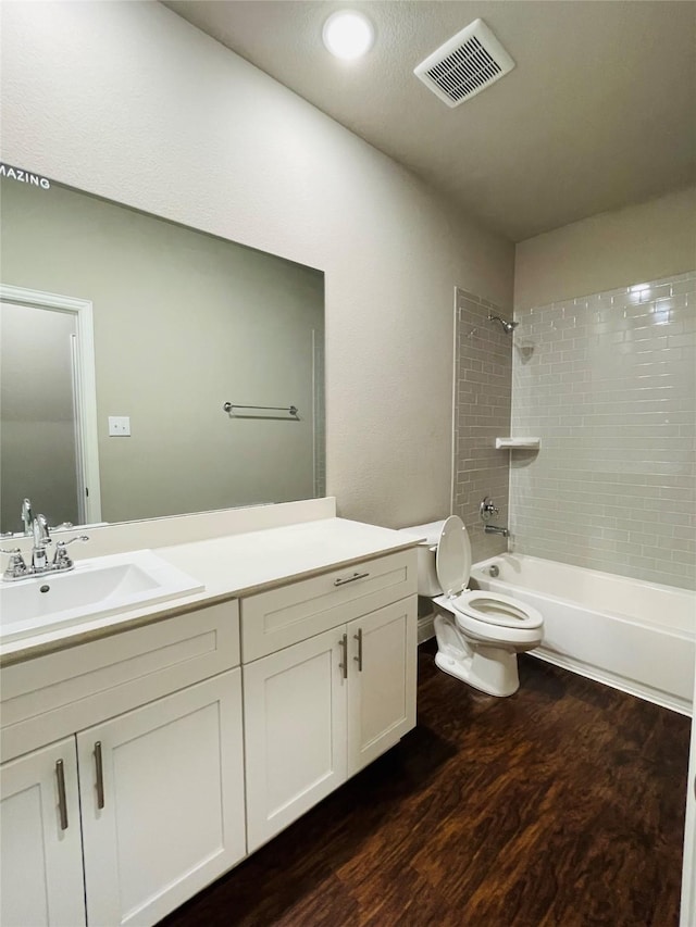 bathroom featuring shower / washtub combination, visible vents, toilet, vanity, and wood finished floors