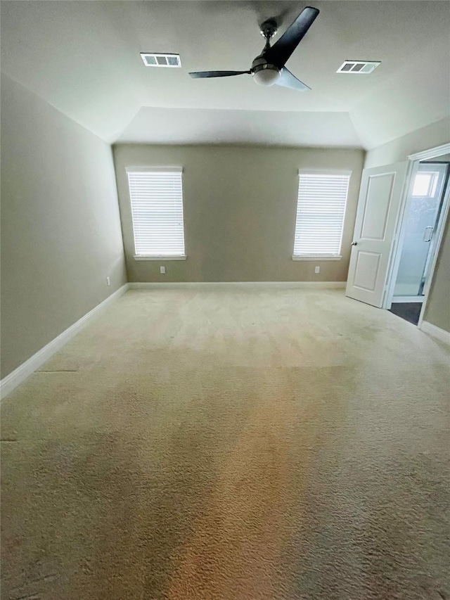 unfurnished bedroom featuring carpet, visible vents, vaulted ceiling, and multiple windows