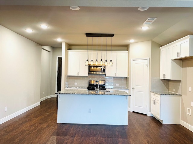 kitchen with light stone counters, stainless steel microwave, a sink, and visible vents