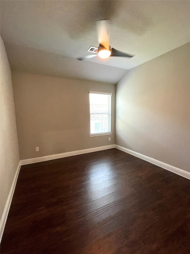 spare room with dark wood-style floors, visible vents, a ceiling fan, a textured ceiling, and baseboards