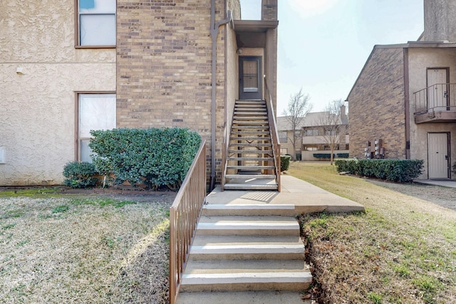 entrance to property with a yard, brick siding, and stucco siding