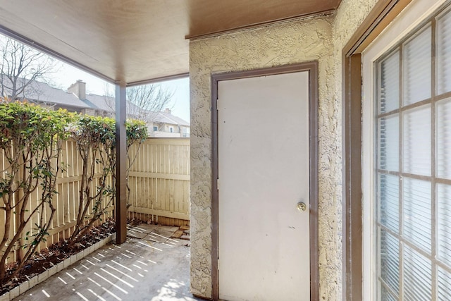 entrance to property featuring fence and stucco siding