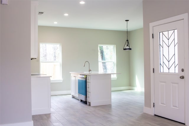 kitchen with light countertops, white cabinets, dishwasher, and a sink