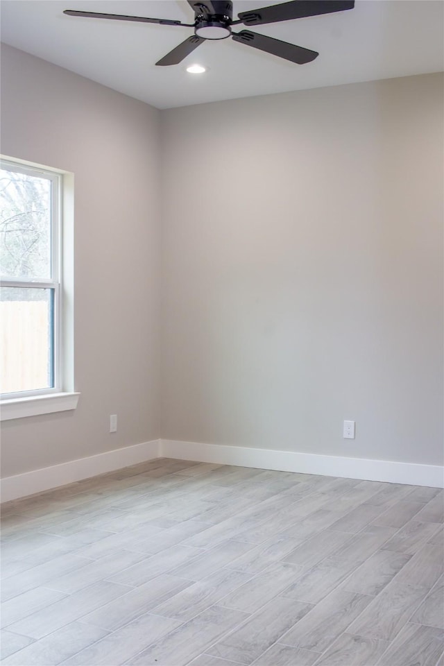 spare room featuring ceiling fan, light wood-style flooring, and baseboards