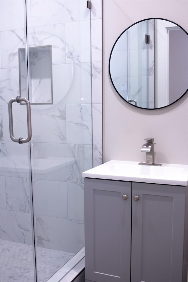 full bath featuring vanity and a marble finish shower