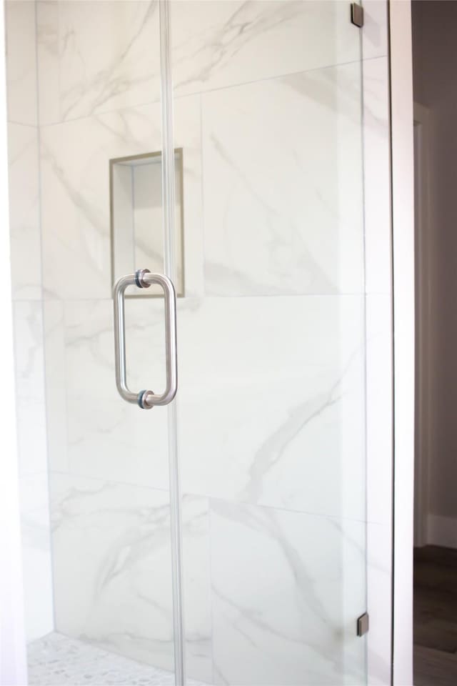 bathroom featuring a marble finish shower