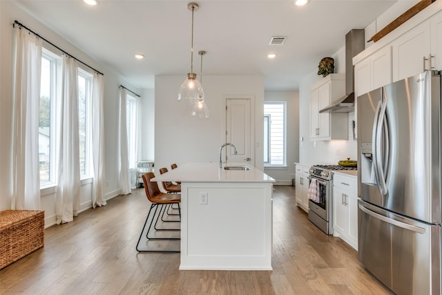 kitchen with appliances with stainless steel finishes, visible vents, a sink, and light wood finished floors