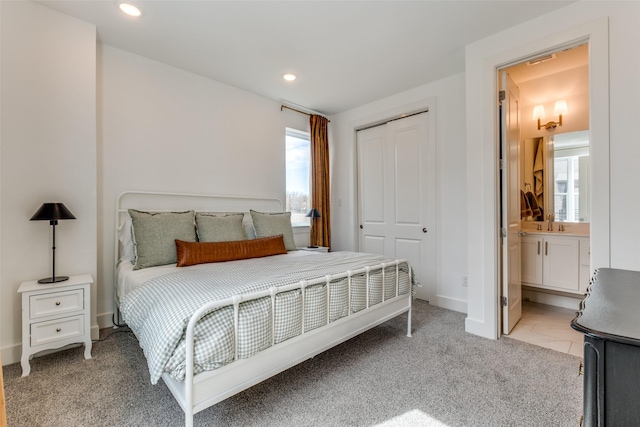 bedroom featuring recessed lighting, a closet, light colored carpet, a sink, and ensuite bath