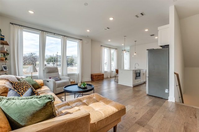 living area with a wealth of natural light, light wood-type flooring, visible vents, and recessed lighting