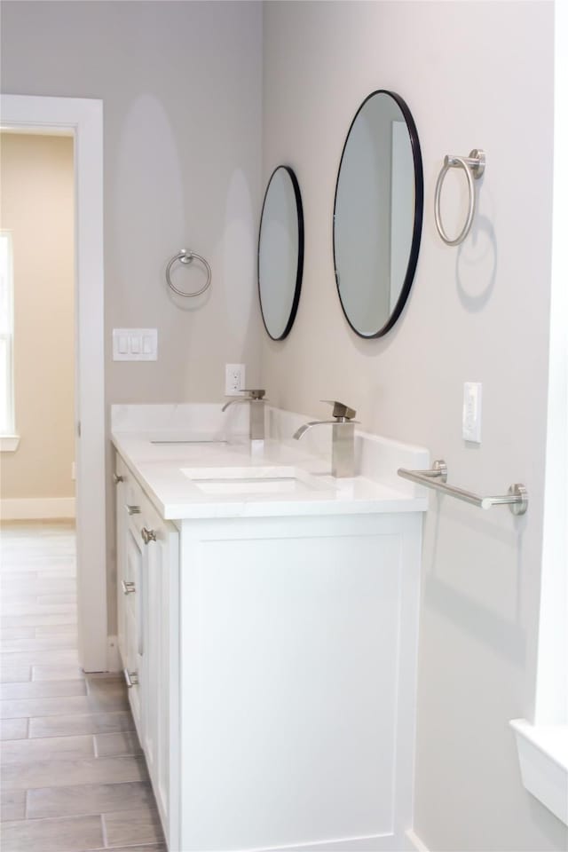 bathroom with baseboards, wood finished floors, and vanity