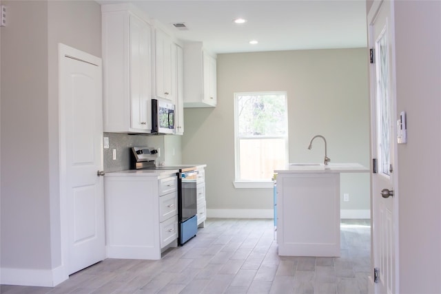 kitchen featuring stainless steel appliances, visible vents, backsplash, white cabinets, and a sink