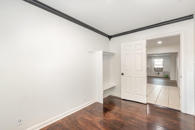 spare room with cooling unit, baseboards, crown molding, and wood finished floors