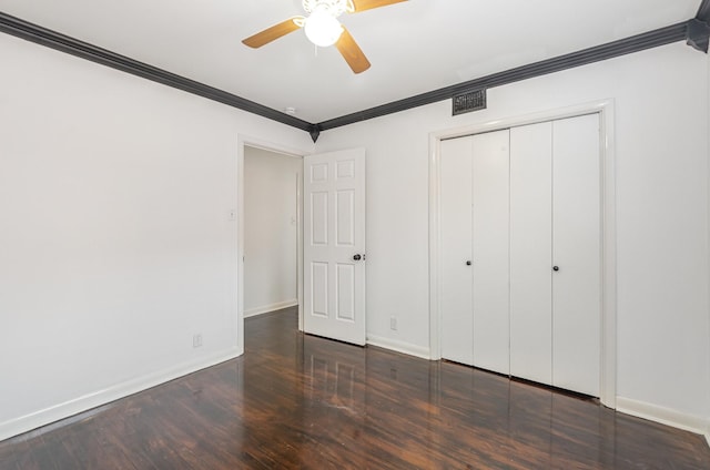 unfurnished bedroom featuring baseboards, ceiling fan, wood finished floors, crown molding, and a closet