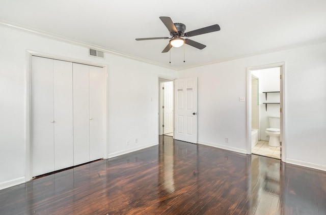 unfurnished bedroom featuring crown molding, a closet, visible vents, wood finished floors, and baseboards