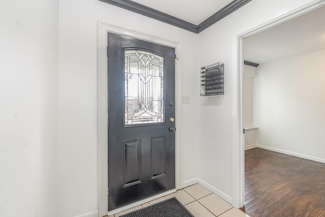 foyer featuring light tile patterned floors, ornamental molding, and baseboards