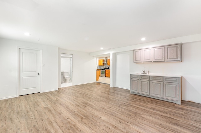 interior space with light wood-style floors, stainless steel range, a sink, and recessed lighting