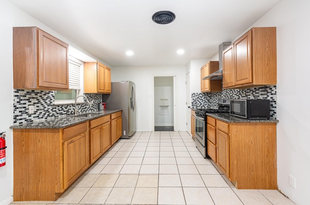 kitchen with decorative backsplash, dark stone countertops, stainless steel appliances, a sink, and light tile patterned flooring