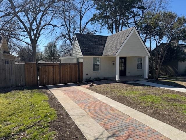 bungalow with a shingled roof, a gate, fence, and stucco siding