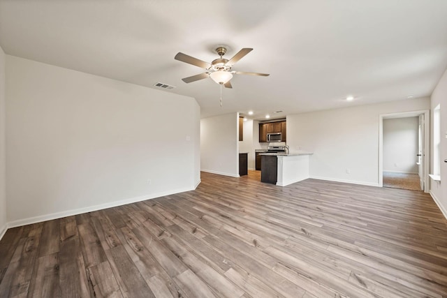 unfurnished living room with recessed lighting, wood finished floors, a ceiling fan, and baseboards