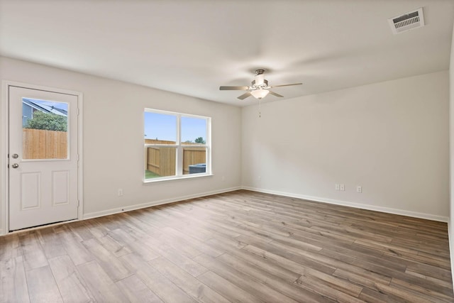 unfurnished room with baseboards, wood finished floors, visible vents, and a healthy amount of sunlight