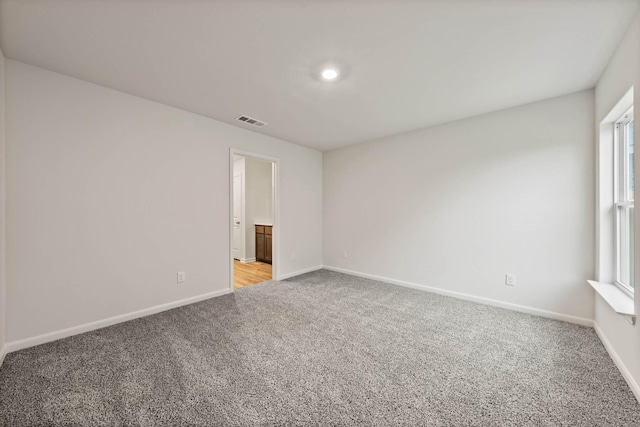 unfurnished room with baseboards, visible vents, and light colored carpet