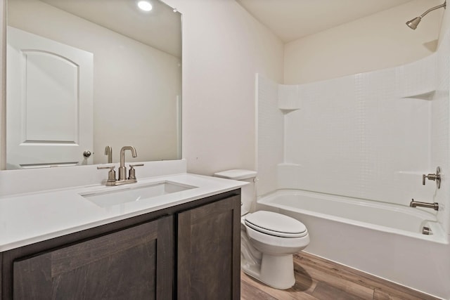 full bathroom featuring washtub / shower combination, vanity, wood finished floors, and toilet