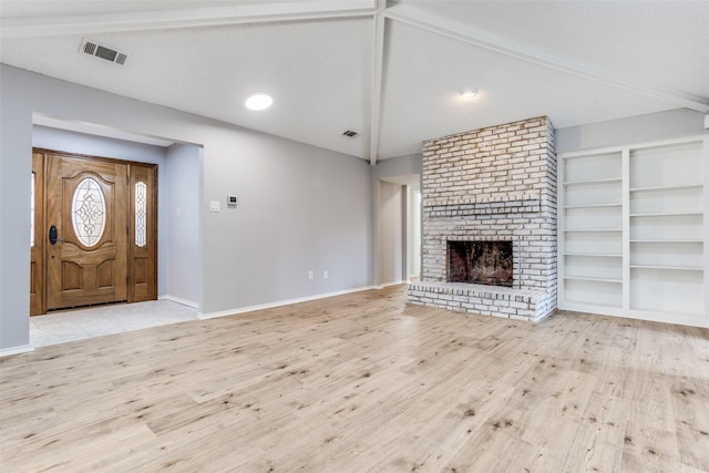 unfurnished living room with vaulted ceiling with beams, a fireplace, visible vents, wood finished floors, and baseboards