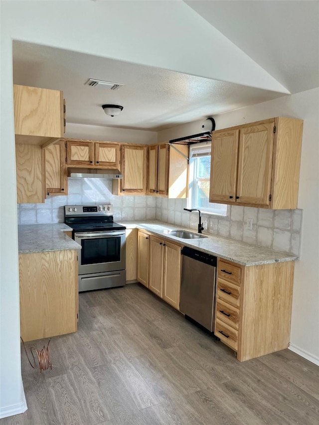 kitchen with under cabinet range hood, a sink, visible vents, appliances with stainless steel finishes, and light brown cabinetry