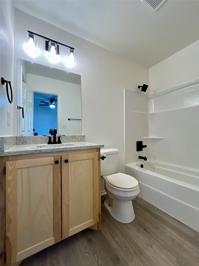 bathroom with toilet, tub / shower combination, wood finished floors, and vanity