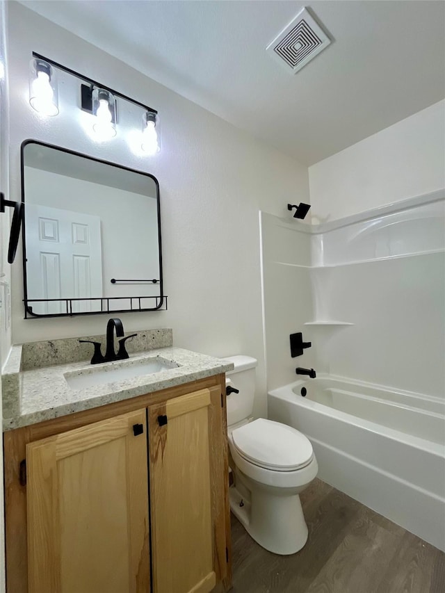 full bath with visible vents, toilet, vanity, shower / tub combination, and wood finished floors