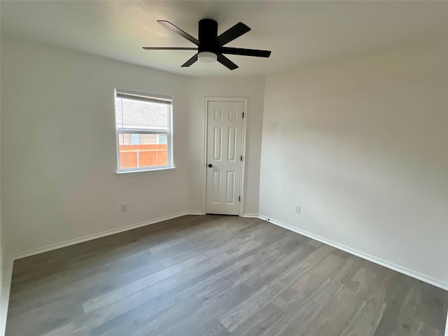 empty room with a ceiling fan, baseboards, and dark wood-style flooring