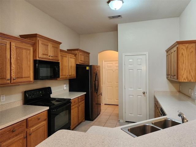 kitchen with arched walkways, light tile patterned floors, a sink, visible vents, and black appliances