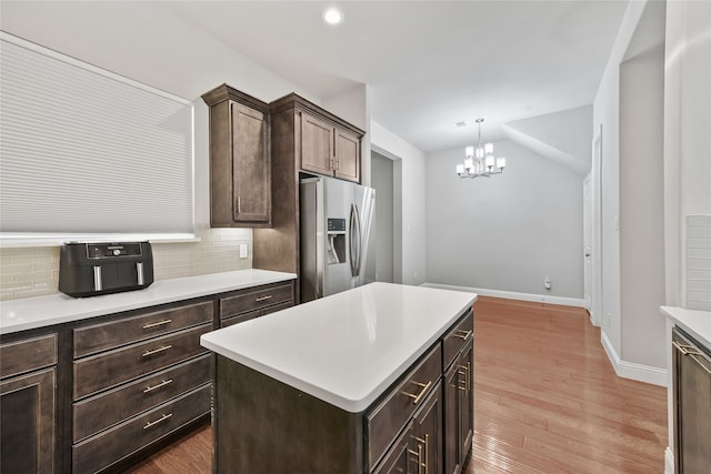 kitchen featuring stainless steel refrigerator with ice dispenser, light countertops, backsplash, dark brown cabinets, and wood finished floors