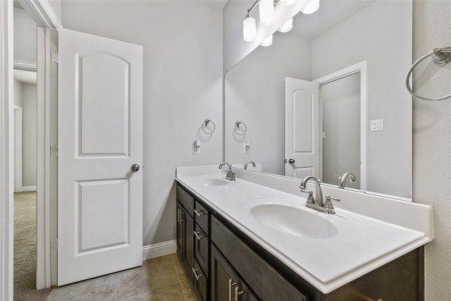 full bathroom with double vanity, a sink, and baseboards