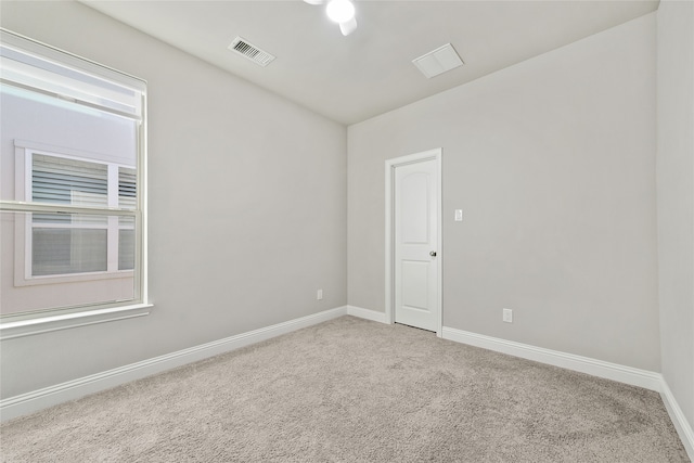 unfurnished room with carpet, visible vents, and baseboards