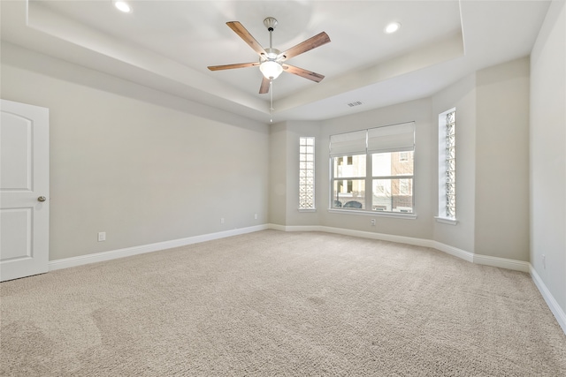 unfurnished room with a raised ceiling, visible vents, light carpet, and baseboards