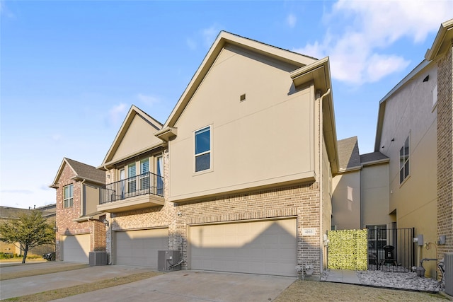 view of home's exterior featuring stucco siding, driveway, central air condition unit, and an attached garage